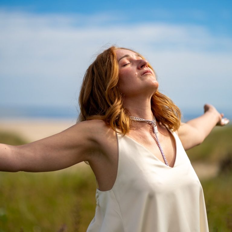 Im Moment ankommen | Body & Soul Stories Frau mit geöffneten Armen im Feld, Gesicht zur Sonne, Moment von Leichtigkeit beim Fotoshooting