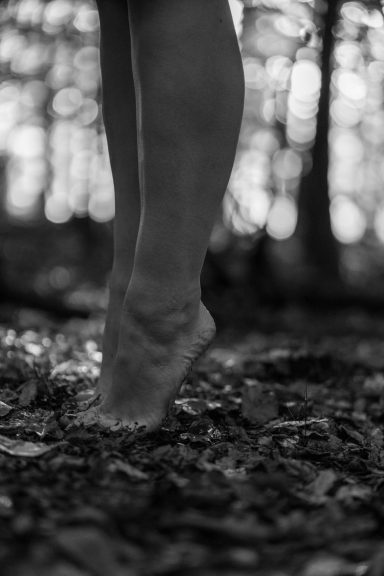Barfüßige Frau geht über Waldboden, Detailaufnahme der Beine, Fotoshooting in der Natur