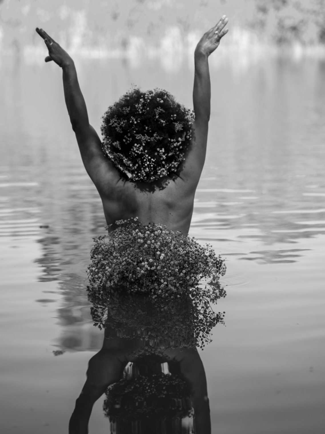 Authentische Frauenfotografie – eine Frau mit Afro Haar steht im Wasser und öffnet sich dem Licht.