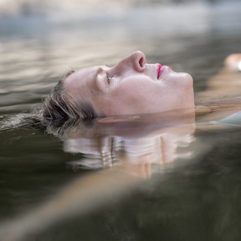 Achtsame Frauenfotografie – Portrait einer Frau im Wasser, die sich entspannt treiben lässt.