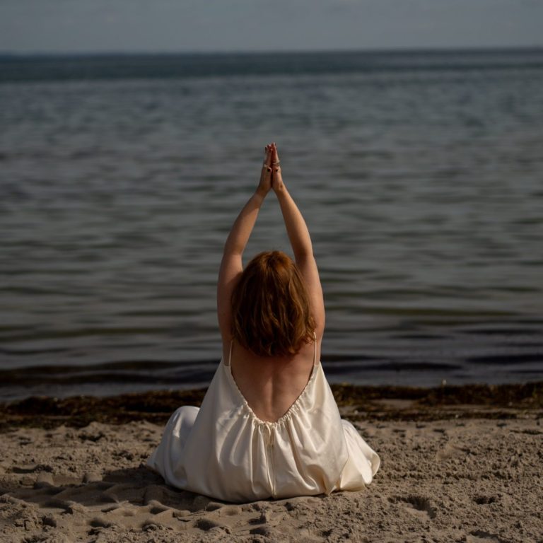 Liebe Silke, Ich freue mich ebenfalls schon sehr auf dich! Der Soulcheck ist für dich kostenlos, hier geht es erstmal darum sich kennen zu lernen und ins spüren zu kommen. Wichtig hier ist dass du dich mit mir sicher fühlst und bereit vor der Kamera auch deine verletzliche Seite zu zeigen. Mein Gefühl sagt mir dass, das „Erblüht“ oder das „Verwurzelt“ shooting für dich die richtigen wären. Frau sitzt im weißen Kleid am Strand, Arme über dem Kopf gestreckt, Blick aufs Meer, Fotoshooting an der Ostsee